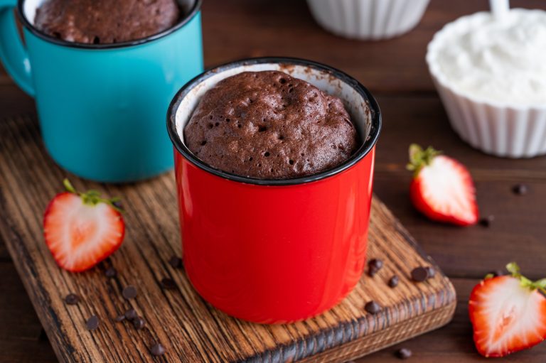 Chocolate mug cake with whipped cream and fresh berries. Cupcake cooked in the microwave